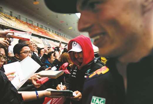Mercedesu2019 British driver Lewis Hamilton (centre) signs autographs next to Red Bullu2019s Dutch driver Max Verstappen (right) prior to the Formula One Chinese Grand Prix in Shanghai yesterday. (AFP)