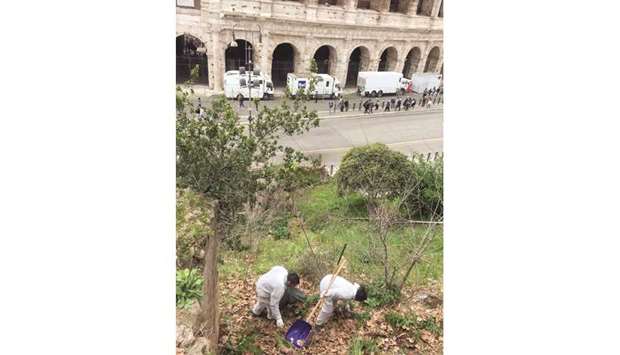 UNDER WATCH: Prisoners, wearing white overalls, clean up rubbish around the Colosseum under the constant surveillance of police officers standing guard.