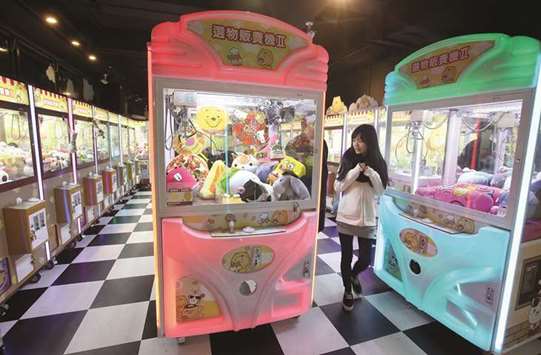 SOARING: A woman inspects claw crane machines at a shop. The number of shops in Taiwan that feature claw crane machines has doubled in the past year.