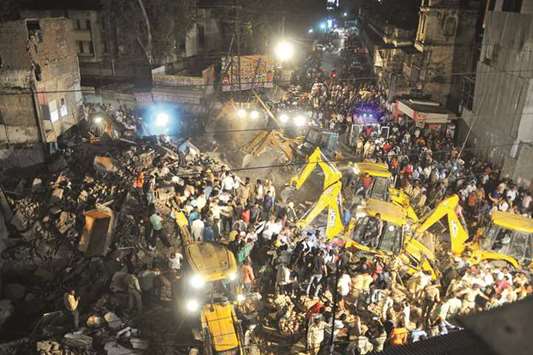 Police, rescue teams and residents take part in rescue operations after a building collapsed in Indore.