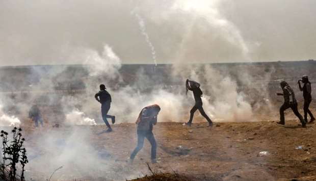 Palestinians take cover from tear gas smoke during clashes with Israeli security forces near border fence with Israel, east of Gaza City in the central Gaza Strip.
