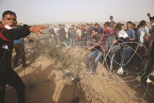 Palestinians try to take down a section of barbed wire at the border fence with Israel, east of Jabalia in the central Gaza city, during a protest, yesterday.