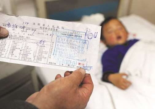 In this file photo taken at a hospital in Hefei, east Chinau2019s Anhui province on November 28, 2011, a parent shows a test result slip confirming that his child has Hepatitis C.