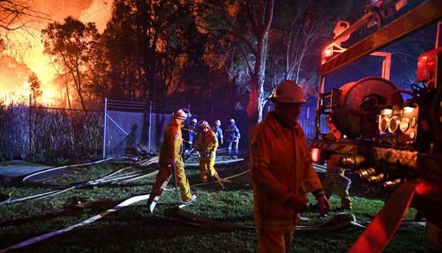 Firefighters fight flames close to homes in Corryton Court, Wattle Grove in Sydney yesterday.
