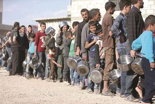 Internally displaced Syrians from eastern Ghouta queue for food in Herjelleh shelter in Damascus countryside, yesterday.