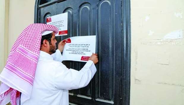 A representative from the MEC posts a notice after the closure of a beauty shop in Khalifa City.