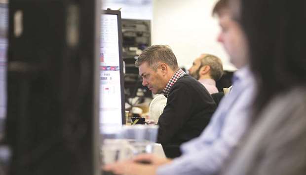 Traders study information on the screens at ETX Capital in central London (file). The commodities-heavy FTSE 100 slipped yesterday as oil prices slid, and shares in BP and Shell both fell.