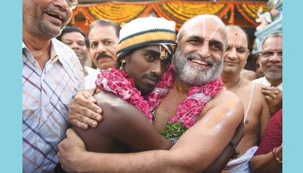 A Hindu priest (right) hugs a Dalit devotee after carrying him on his shoulders into the sanctum sanctorum of the Sri Ranganatha temple in Hyderabad yesterday. The re-enactment of 2,700-year-old ritual known as u2018Munivahana Sevau2019 was held to emphasise the equality of humans, in the wake of atrocities in India against so-called u201cloweru201d caste communities and the alleged dilution of a law to ensure their protection.