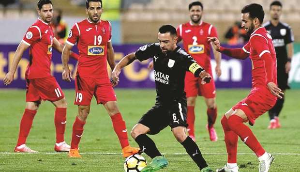 Al-Saddu2019s Xavi Hernandez (centre) dribbles the ball as Persepolisu2019 Ahmad Noorollahi defends during the AFC Champions League match at the Azadi Stadium in Tehran yesterday. (AFP)