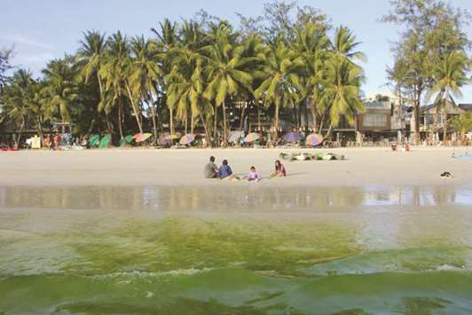 Tourists relax as algae turns the water green at Boracay beach, Malay town, in central Philippines, yesterday, ahead of its closure.