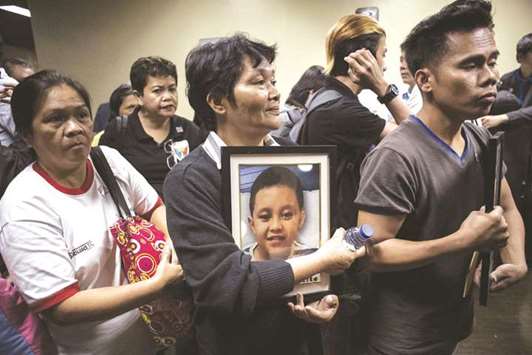 File photo shows Melinda Colite (centre) holding a picture of her grandson Zandro Colite, who she says died after getting injected with the anti-dengue fever vaccine Dengvaxia, during a Senate investigation about the vaccine in Manila.