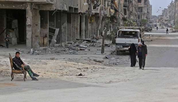 Civilians walk in the former Syrian town of Douma on the outskirts of Damascus