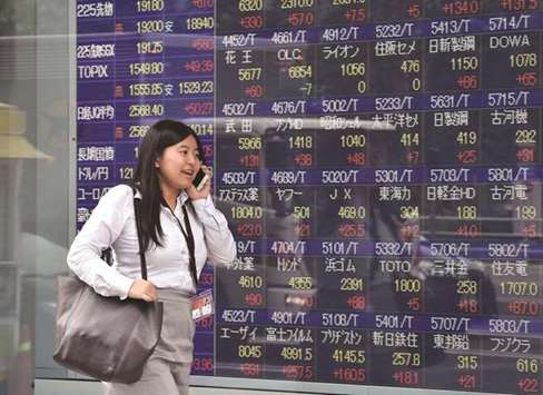 A woman passes before a share prices board in Tokyo. The Nikkei 225 closed up 1.4% to 22,158.20 points yesterday.