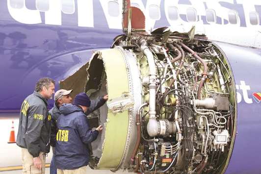 National Transportation Safety Board investigators examine damage to the engine of the Southwest Airlines plane yesterday.