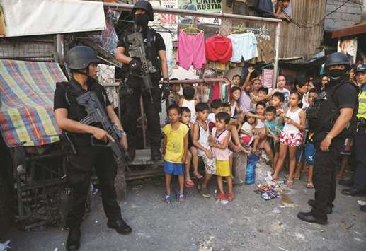 File photo shows members of Philippine National Police SWAT team standing guard near residents during an anti-drugs operation, in Pasig, Metro Manila.
