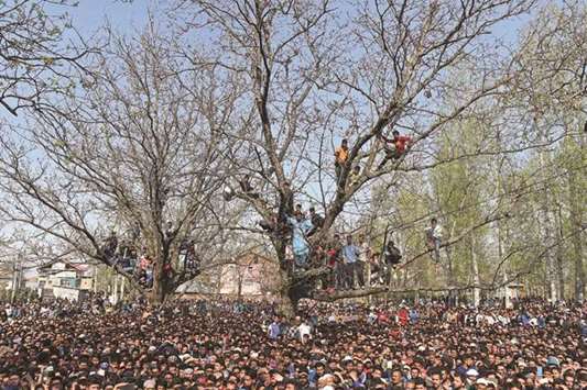 Villagers stand on a tree as they look at a funeral procession of a militant killed in Shopian, south of Srinagar yesterday.