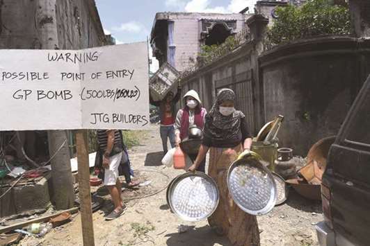 Residents carry belongings collected from their destroyed house during a visit to the main battle area in Marawi City, in the southern island of Mindanao, yesterday.