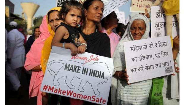 A girl holding a placard is carried by her mother as they attend a protest against rape in Unnao, Uttar Pradesh