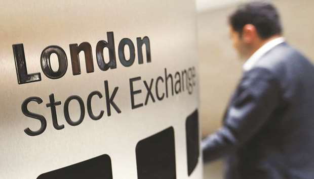 A visitor passes a London Stock Exchange sign inside the main atrium of the London Stock Exchange Group headquarters in London. The FTSE 100 index gained 0.5% at 7,348.17 points yesterday.