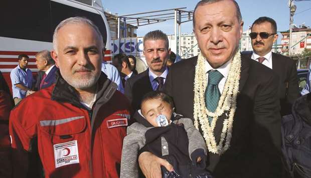This handout picture taken and released by the Turkish Presidential Press Service yesterday in Hatay shows Head of the Turkish Red Crescent, Kerem Kinik (left) and Turkish President Recep Tayyip Erdogan holding Syrian infant Karim Abdel Rahman, during  Erdoganu2019s visit to border units.