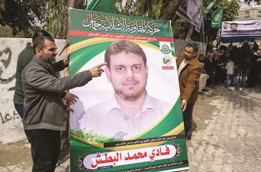 A picture taken yesterday shows men holding up a poster portrait of 35-year-old Palestinian professor and Hamas member Fadi Mohamed al-Batsh who was killed early in the day in Malaysia, outside his familyu2019s house in Jabalia in the northern Gaza strip.