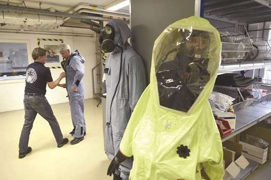 A man tries on an air permeable charcoal impregnated suit, combined with a respirator (or gas mask), rubber boots and three layers of gloves during a simulation at the OPCW headquarters in The Hague, The Netherlands.