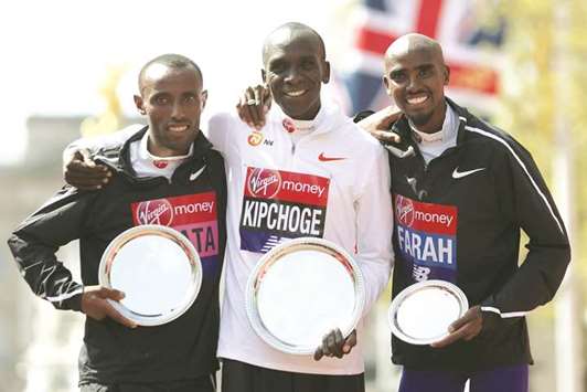 Winner Kenyau2019s Eliud Kipchoge (centre), second-placed Ethiopiau2019s Tola Shura Kitata (left) and third-placed Britainu2019s Mo Farah pose at the podium ceremony of the London Marathon in London yesterday. (AFP)