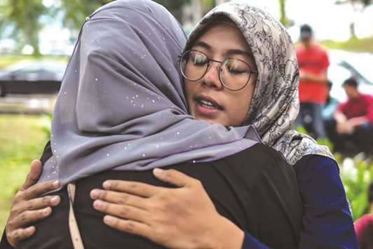 Students of Palestinian professor Fadi al-Batsh, who was killed in a drive-by shooting on April 21, hug each other outside the compound of the forensic wing of the Hospital Selayang in Kuala Lumpur.
