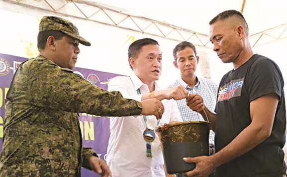 Special Assistant to the President Christopher u201cBongu201d Go hands a pail of groceries to one of the fishermen repatriated from Indonesia, watched by Eastern Mindanao Command chief Lt Gen Benjamin Madrial Jr.