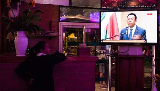 A woman at a restaurant watches national television broadcasting President Hery Rajaonarimampianina addressing the nation, in Antananarivo.