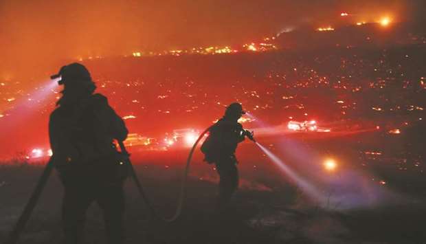 A December 7, 2017, file photo of  firefighters walking to the fire line at the Lilac fire in Bonsall, California.