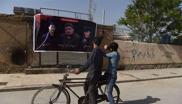 Afghan residents take photographs of a banner with the image of Wakil Hussain Allahdad (centre), one of the 60 victims of a bomb blast in Kabul.