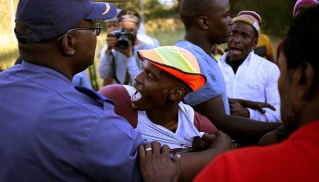 A police officer restrains a protester during protests in Mahikeng, in the North West province, South Africa, on April 20.
