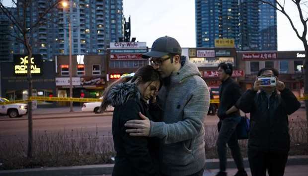 People embrace at the scene of a memorial for victims of a crash at Yonge St. at Finch Ave., after a van plowed into pedestrians on April 23, 2018 in Toronto, Canada. AFP