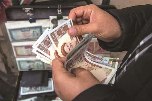 A currency trader counts Iranian rial banknotes at a money exchange market on Ferdowsi street in Tehran (file). Finding a bank in Iran is easy. The challenge is finding one that will lend at affordable rates, or even lend at all.