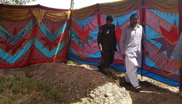 Pakistani policemen walk beside the grave of Italian national of Pakistani origin Sana Cheema, who was allegedly killed by her family members, in Gujrat of Pakistan's Punjab province