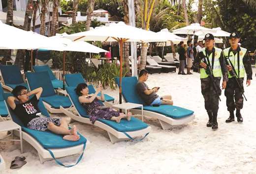 Policemen walk past tourists, one day before the temporary closure of the holiday island Boracay, yesterday.