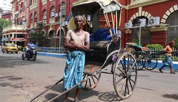 Mohammad Ashgar, 65, an Indian rickshaw puller, poses for a photograph next to his rickshaw in Kolkata.