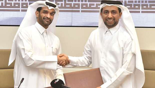 Hassan al-Thawadi and Hassan al-Derham shaking hands after signing the agreement.