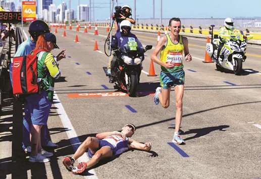 Callum Hawkins of Scotland lies on the ground as Michael Shelley (right) of Australia runs past during the menu2019s Marathon Final at the Commonwealth Games in Gold Coast, Australia, yesterday. (Reuters)