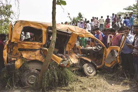 People inspect the school van that was hit by a train at an unmanned railroad crossing near Kushinagar in Uttar Pradesh yesterday.