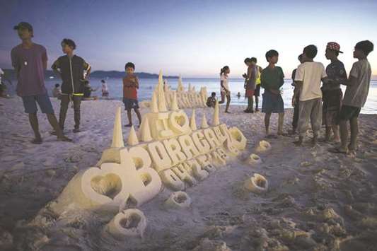 Tourists standing beside a sand castle on the island of Boracay in this file picture.