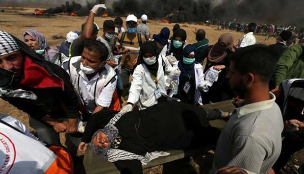 A woman demonstrator is evacuated after inhaling tear gas fired by Israeli troops during clashes at a protest where Palestinians demand the right to return to their homeland, at the Israel-Gaza border in the southern Gaza Strip.