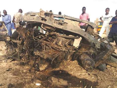People look at a vehicle destroyed by the military during cross fire with Boko Haram militants which killed at least four, in Maiduguri, yesterday.