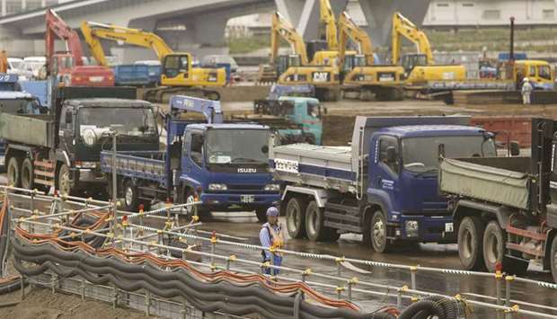 A man stands next to trucks as he controls the traffic at a construction site in Tokyo. Japanu2019s industrial output rose 1.2% in March from February, the data showed,  beating the median forecast for a 0.5% increase and followed a 2% rise in February.