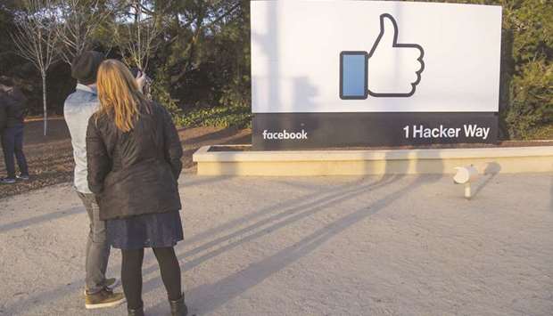 Pedestrians take photographs of signage displayed outside Facebook  headquarters in Menlo Park, California. Facebook said monthly active users in the first quarter rose to 2.2bn, up 13% from a year earlier and matching expectations, according to Thomson Reuters I/B/E/S.