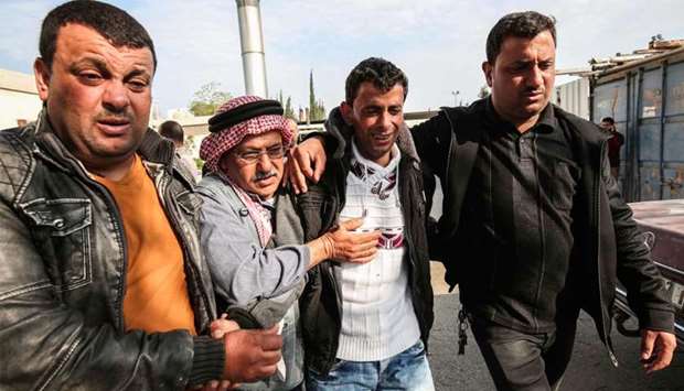 The father (C-R) of Palestinian teenager Azzam Oueida is consoled by others as he walks outside the hospital