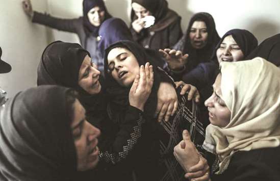 Mourners console the mother (centre) of 15-year-old Palestinian teenager Azzam Aweida during his funeral in Khan Yunis in the southern Gaza Strip, yesterday.