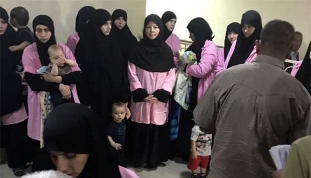 Russian women who have been sentenced to life in prison on grounds of joining the Islamic State group standing with children in a hallway of Baghdad's Central Criminal Court on Sunday.