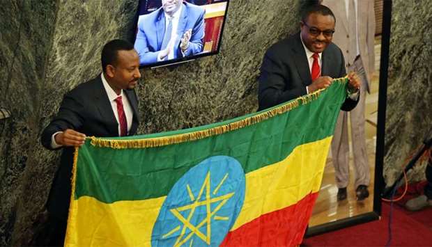 Ethiopia's new Prime Minister Abiye Ahmed and outgoing  Prime Minister Hailemariam Desalegn hold the national flag